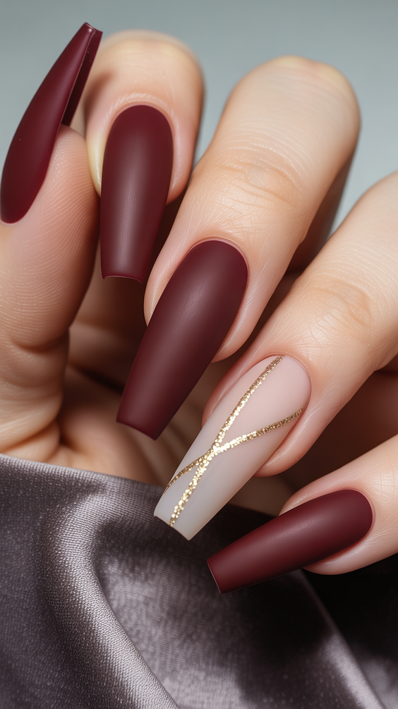coffin nail designs 2026 Matte Burgundy Coffin Nails With Minimal Gold Line Accent